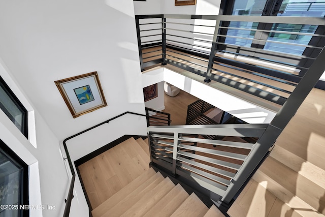 stairs with wood-type flooring and a towering ceiling