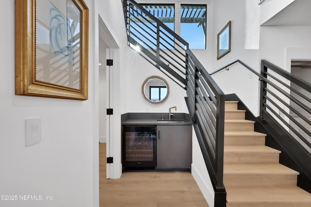 staircase with wine cooler, hardwood / wood-style flooring, and wet bar