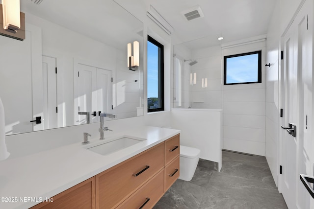 bathroom featuring a tile shower, vanity, and toilet