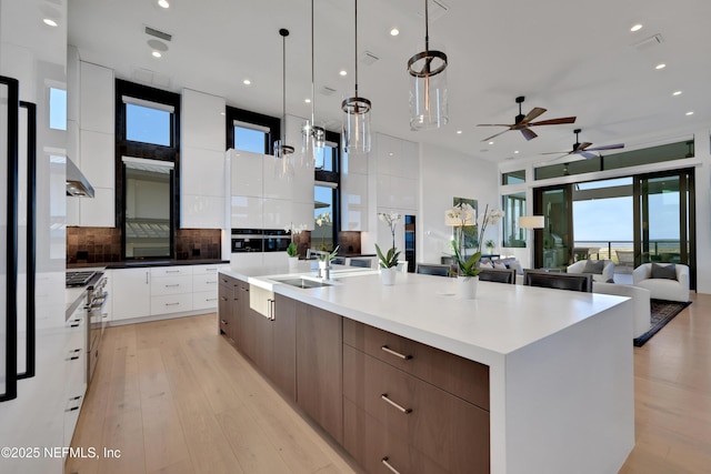 kitchen featuring tasteful backsplash, sink, pendant lighting, white cabinetry, and a large island