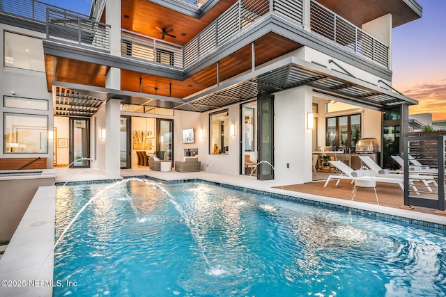 pool at dusk with ceiling fan and pool water feature