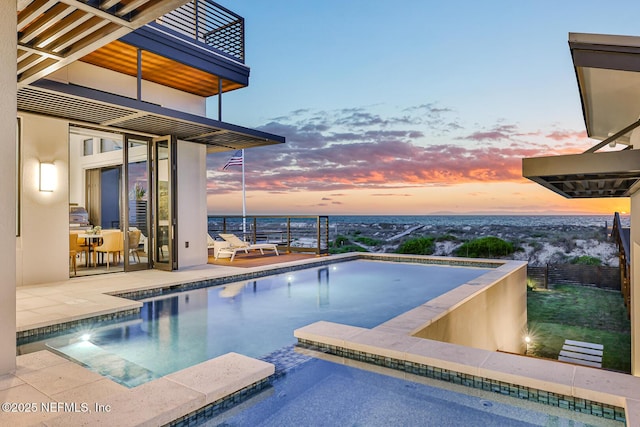 pool at dusk with a hot tub