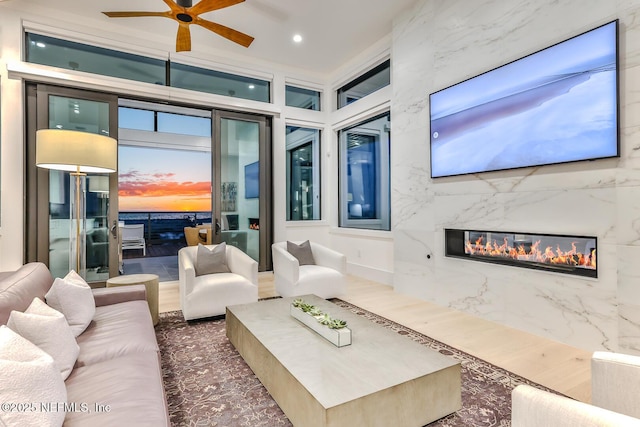 living room with ceiling fan and a high end fireplace