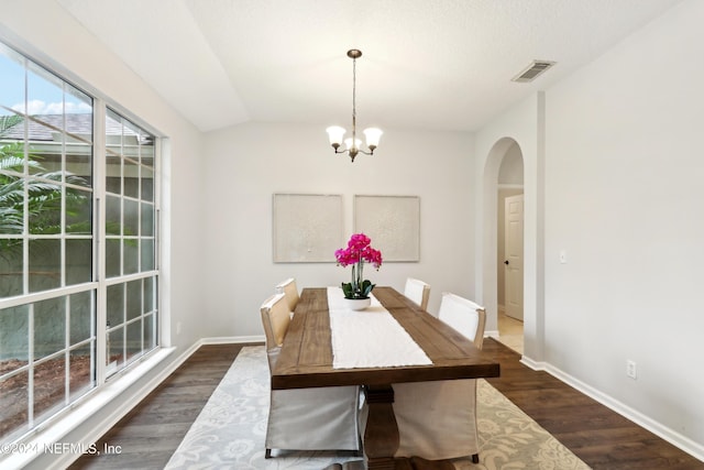 unfurnished dining area featuring a textured ceiling, a notable chandelier, dark wood-type flooring, and vaulted ceiling