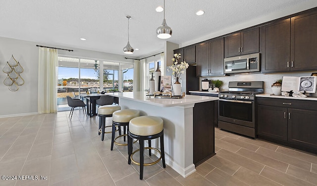 kitchen featuring dark brown cabinetry, a kitchen island, pendant lighting, and appliances with stainless steel finishes