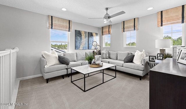 carpeted living room featuring ceiling fan and a textured ceiling