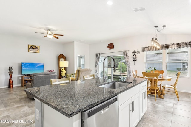 kitchen with white cabinets, a center island with sink, sink, stainless steel dishwasher, and dark stone countertops