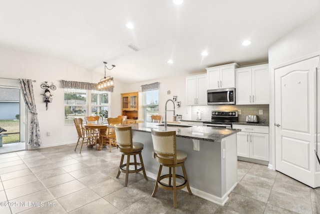 kitchen featuring sink, white cabinetry, stainless steel appliances, and a kitchen island with sink