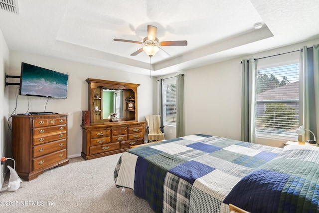 carpeted bedroom featuring ceiling fan and a raised ceiling