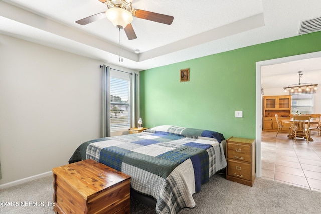 bedroom with a raised ceiling, ceiling fan, and tile patterned flooring