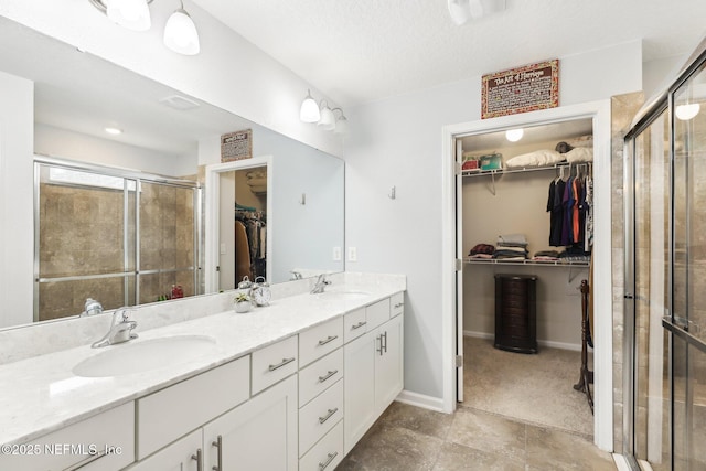 bathroom featuring vanity, a shower with shower door, and a textured ceiling