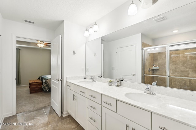 bathroom with ceiling fan, a textured ceiling, vanity, and walk in shower