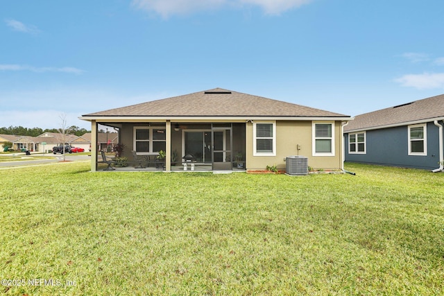 rear view of house with central air condition unit, a lawn, and a sunroom