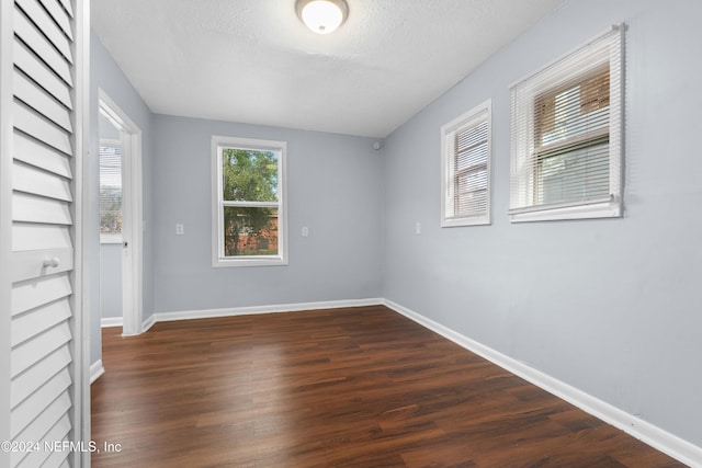 spare room featuring dark hardwood / wood-style flooring and a textured ceiling