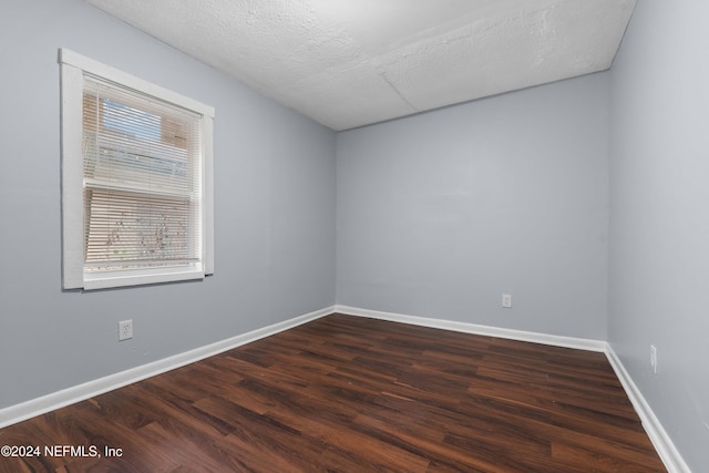 empty room featuring dark hardwood / wood-style flooring and a textured ceiling