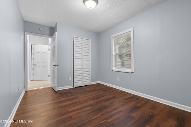 unfurnished bedroom featuring dark hardwood / wood-style floors, a textured ceiling, and a closet