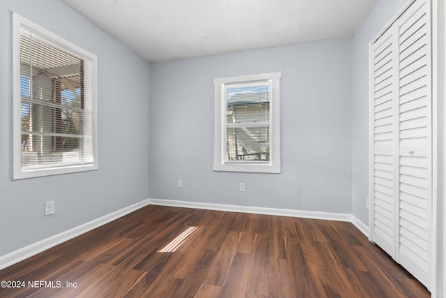 unfurnished bedroom with dark hardwood / wood-style flooring and a closet