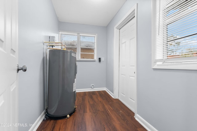 clothes washing area with a wealth of natural light, electric water heater, and dark hardwood / wood-style flooring