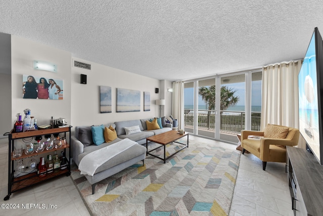 living room with a textured ceiling and a wall of windows