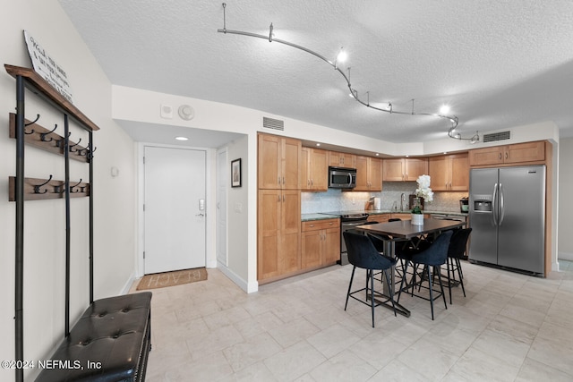 kitchen featuring stainless steel appliances, tasteful backsplash, a textured ceiling, a breakfast bar area, and a kitchen island