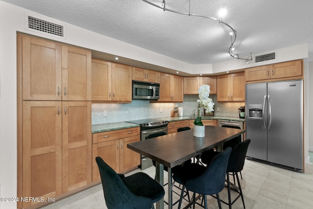 kitchen featuring rail lighting, tasteful backsplash, a textured ceiling, stainless steel appliances, and sink