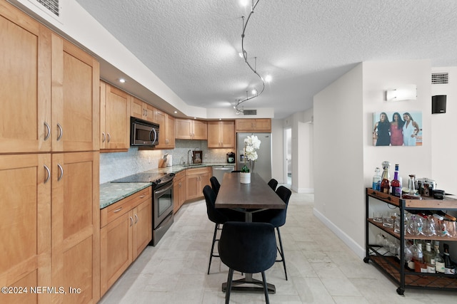 kitchen featuring a center island, rail lighting, stainless steel appliances, a kitchen breakfast bar, and decorative backsplash