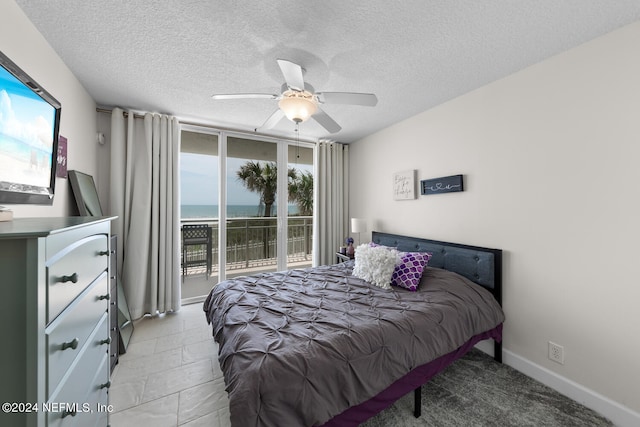 bedroom with ceiling fan, a water view, a textured ceiling, and access to outside