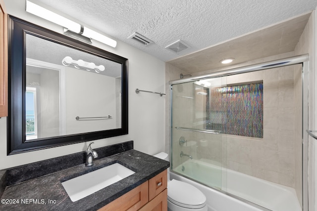 full bathroom with combined bath / shower with glass door, a textured ceiling, vanity, and toilet