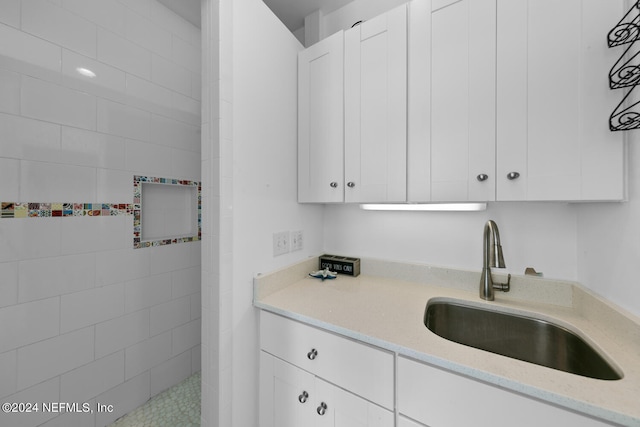 kitchen featuring light stone counters, white cabinetry, and sink