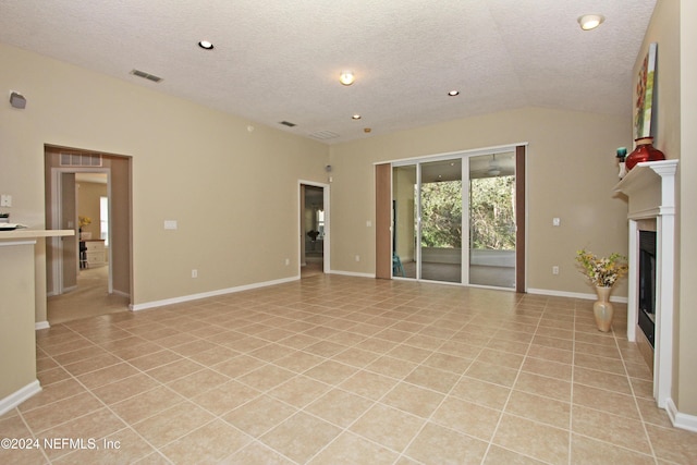 unfurnished living room featuring vaulted ceiling, light tile patterned floors, and a textured ceiling