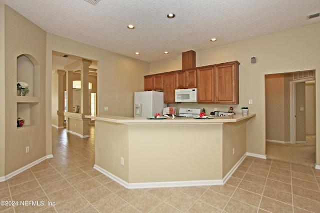 kitchen featuring light tile patterned floors, white appliances, kitchen peninsula, a textured ceiling, and built in shelves