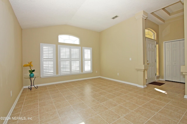 tiled empty room with lofted ceiling and a textured ceiling