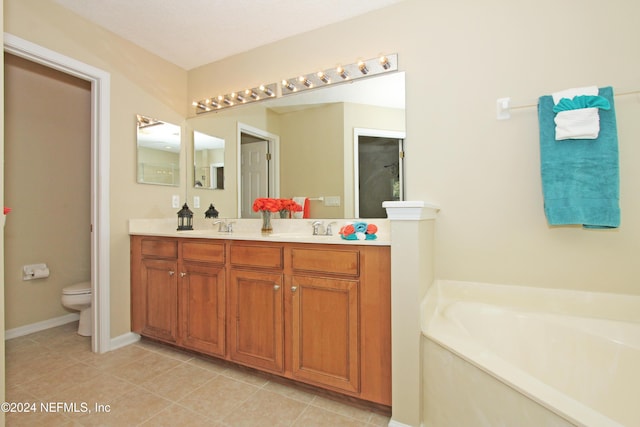 bathroom featuring vanity, a bath, tile patterned floors, and toilet