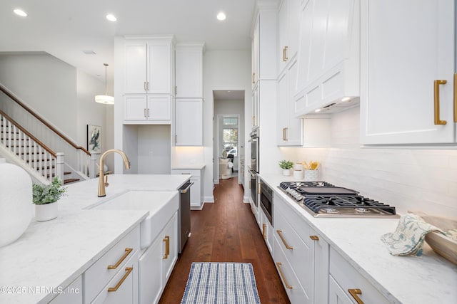 kitchen featuring white cabinetry, light stone counters, sink, and decorative light fixtures