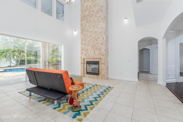 living room with a tile fireplace, light tile patterned flooring, a chandelier, and a high ceiling