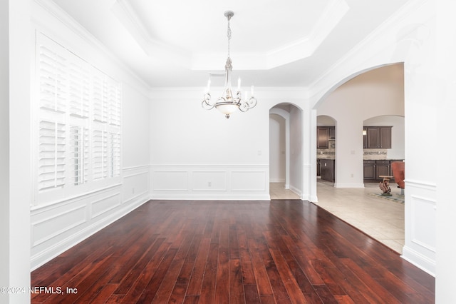 unfurnished room featuring hardwood / wood-style flooring, a chandelier, crown molding, and a tray ceiling