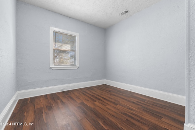 spare room with dark hardwood / wood-style flooring and a textured ceiling