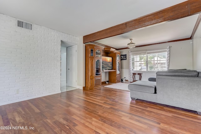 unfurnished living room with crown molding, beamed ceiling, brick wall, and hardwood / wood-style flooring