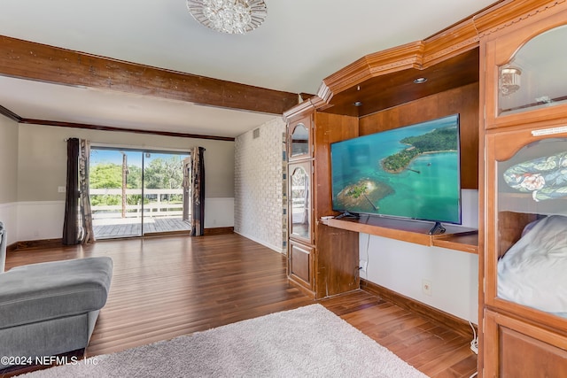 unfurnished living room with beamed ceiling, ornamental molding, a chandelier, and dark wood-type flooring