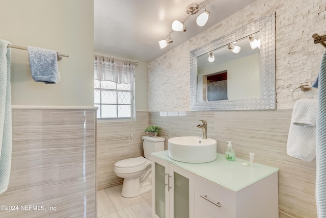 bathroom with tile patterned flooring, vanity, tile walls, and toilet