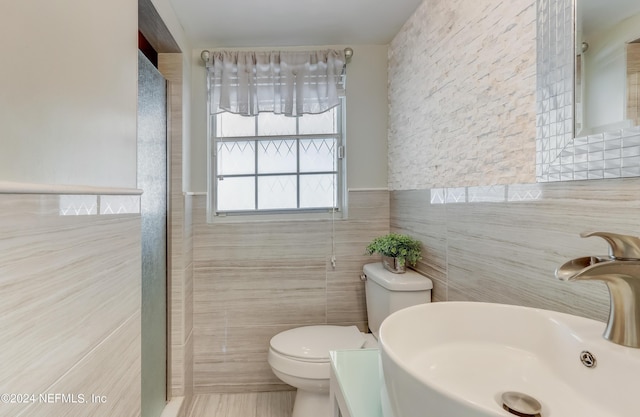 bathroom with toilet, tile walls, and sink