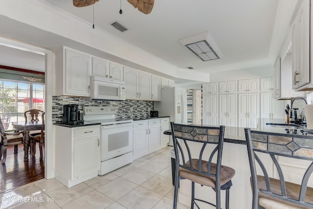 kitchen with white cabinetry, sink, light tile patterned floors, and white appliances