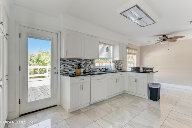 kitchen featuring white dishwasher, sink, decorative backsplash, white cabinetry, and kitchen peninsula