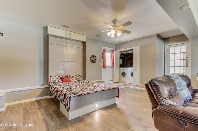 bedroom featuring ceiling fan, washer and clothes dryer, and light wood-type flooring