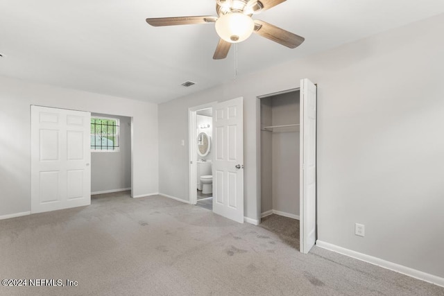 unfurnished bedroom featuring a closet, connected bathroom, light colored carpet, and ceiling fan