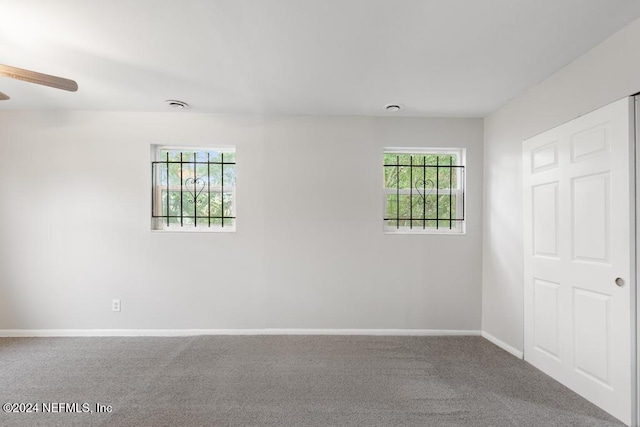 unfurnished room with ceiling fan and carpet