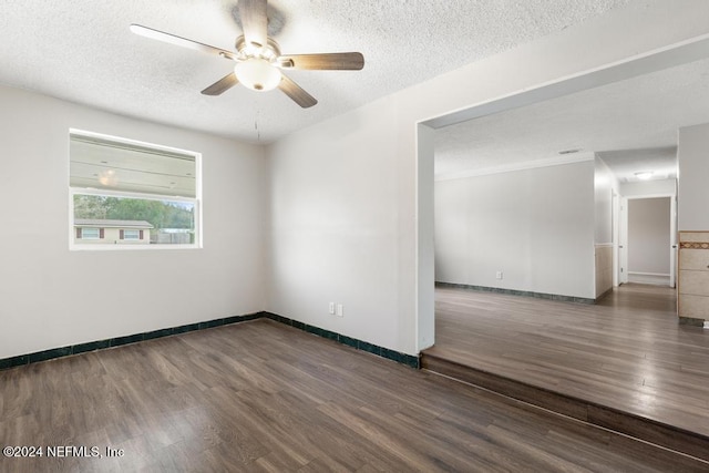 empty room with a textured ceiling, ceiling fan, and dark hardwood / wood-style floors