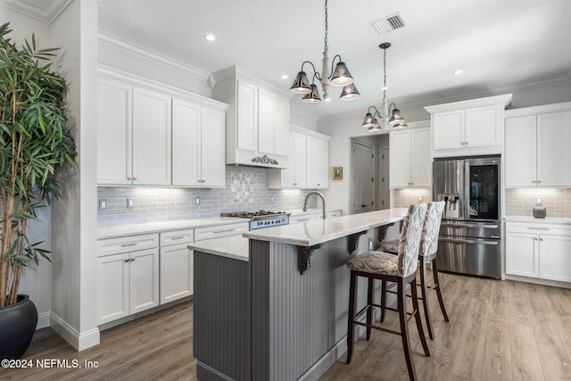 kitchen featuring white cabinets, light stone counters, stainless steel fridge with ice dispenser, and an island with sink