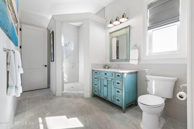 bathroom featuring a tile shower, vanity, and toilet