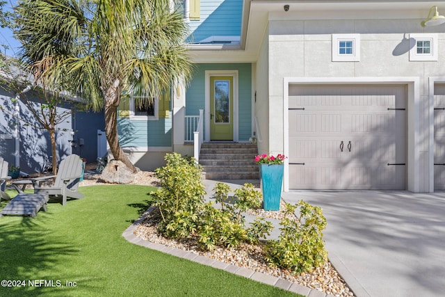 view of exterior entry with a yard and a garage